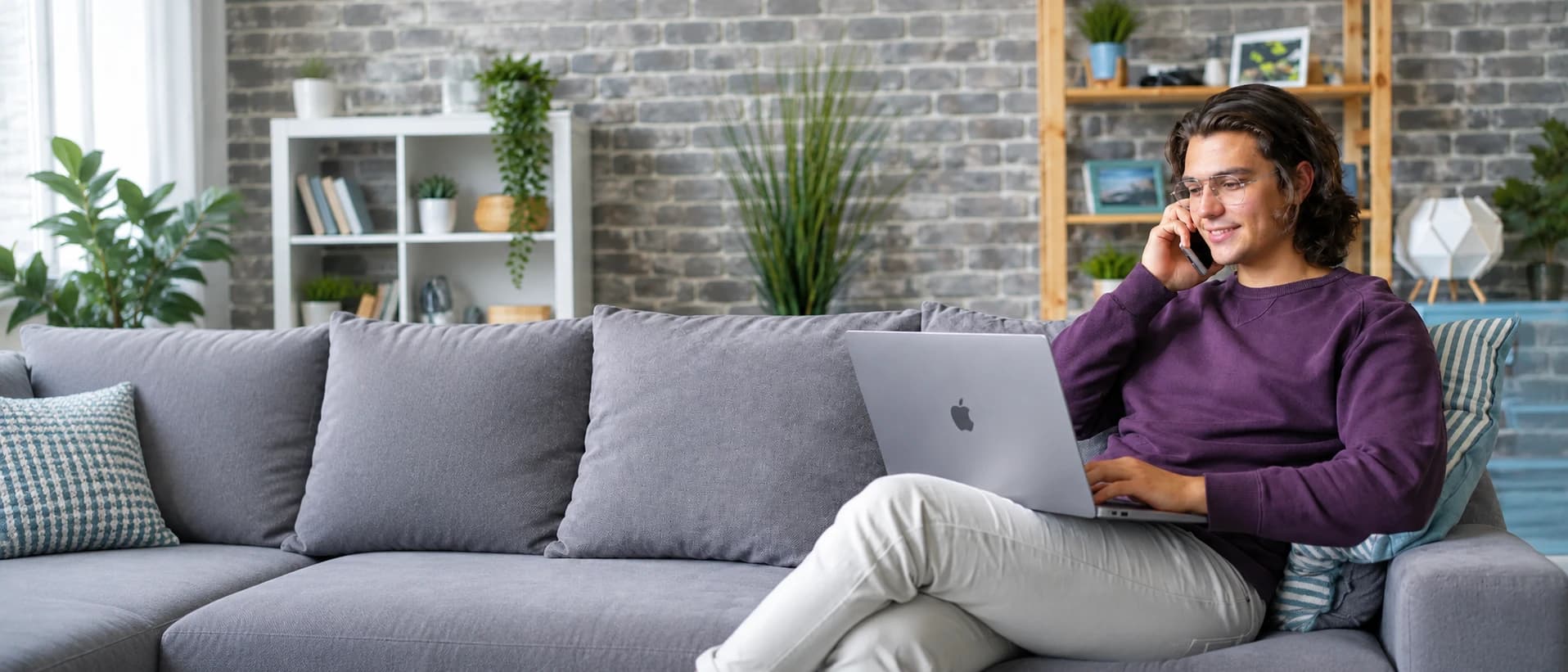 Person i soffan med laptop i knät, mitt i ett telefonsamtal